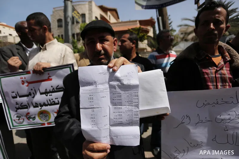 Palestinians employed by the Palestinian Authority, chant slogans and wave placards during a demonstration against the decision to reduce their salaries in Gaza City on April 11, 2017. Photo by Ashraf Amra