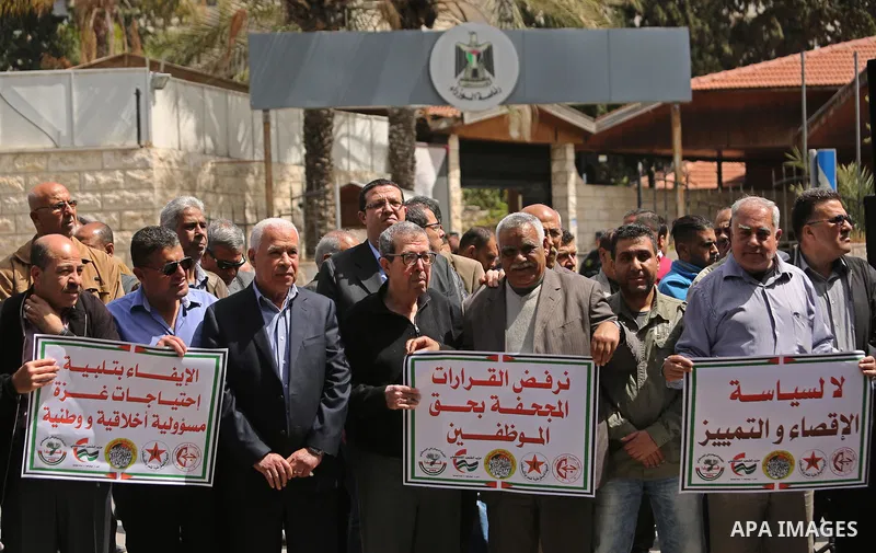 Palestinians employed by the Palestinian Authority, chant slogans and wave placards during a demonstration against the decision to reduce their salaries in Gaza City on April 11, 2017. Photo by Ashraf Amra
