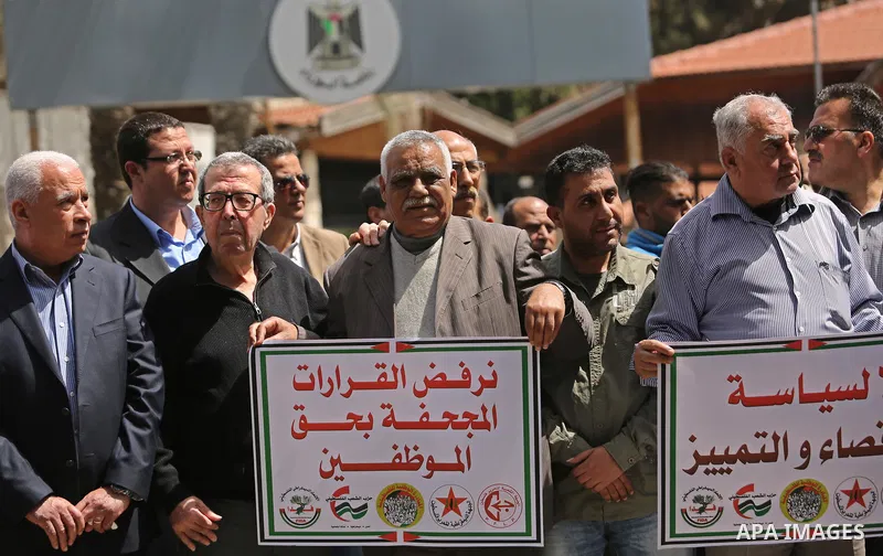 Palestinians employed by the Palestinian Authority, chant slogans and wave placards during a demonstration against the decision to reduce their salaries in Gaza City on April 11, 2017. Photo by Ashraf Amra