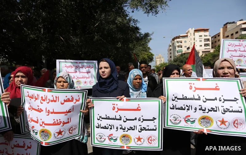 Palestinians employed by the Palestinian Authority, chant slogans and wave placards during a demonstration against the decision to reduce their salaries in Gaza City on April 11, 2017. Photo by Ashraf Amra