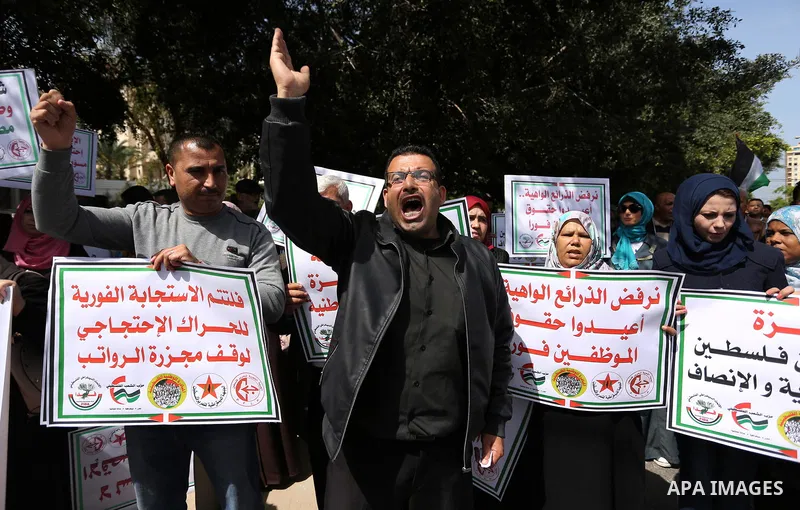 Palestinians employed by the Palestinian Authority, chant slogans and wave placards during a demonstration against the decision to reduce their salaries in Gaza City on April 11, 2017. Photo by Ashraf Amra