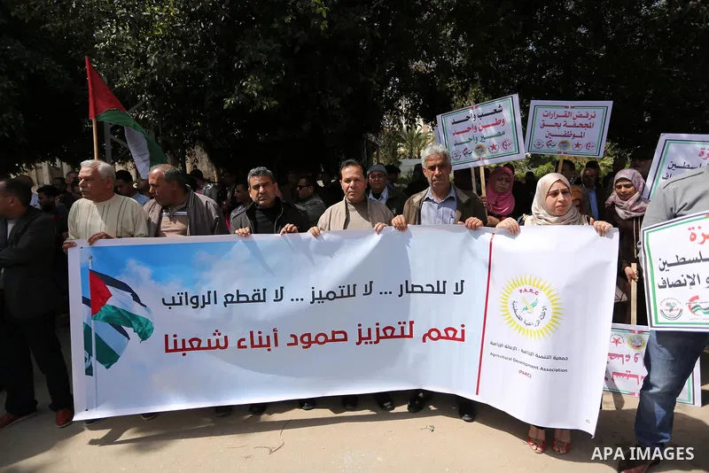 Palestinians employed by the Palestinian Authority, chant slogans and wave placards during a demonstration against the decision to reduce their salaries in Gaza City on April 11, 2017. Photo by Ashraf Amra