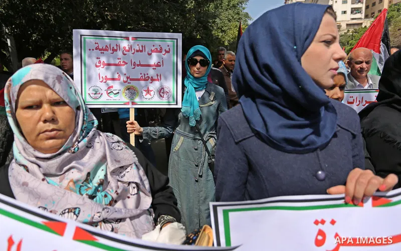 Palestinians employed by the Palestinian Authority, chant slogans and wave placards during a demonstration against the decision to reduce their salaries in Gaza City on April 11, 2017. Photo by Ashraf Amra