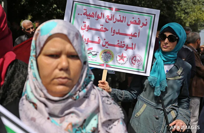 Palestinians employed by the Palestinian Authority, chant slogans and wave placards during a demonstration against the decision to reduce their salaries in Gaza City on April 11, 2017. Photo by Ashraf Amra