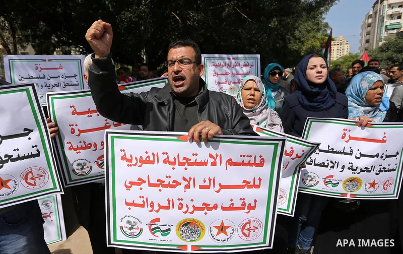 Palestinians employed by the Palestinian Authority, chant slogans and wave placards during a demonstration against the decision to reduce their salaries in Gaza City on April 11, 2017. Photo by Ashraf Amra