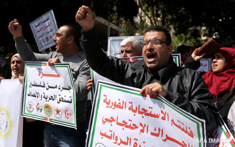 Palestinians employed by the Palestinian Authority, chant slogans and wave placards during a demonstration against the decision to reduce their salaries in Gaza City on April 11, 2017. Photo by Ashraf Amra
