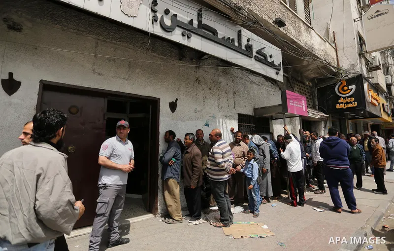 Palestinians of Social Affairs wait in front of Bank of Palestine to withdrew their financial aid in Gaza City on April 11, 2017. Photo by Ashraf Amra