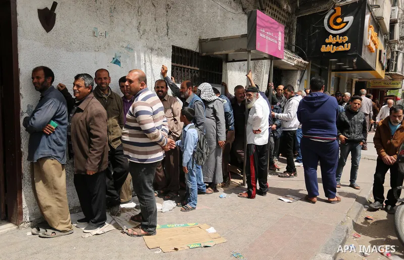 Palestinians of Social Affairs wait in front of Bank of Palestine to withdrew their financial aid in Gaza City on April 11, 2017. Photo by Ashraf Amra