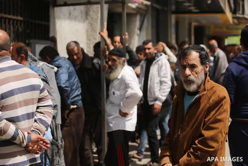 Palestinians of Social Affairs wait in front of Bank of Palestine to withdrew their financial aid in Gaza City on April 11, 2017. Photo by Ashraf Amra