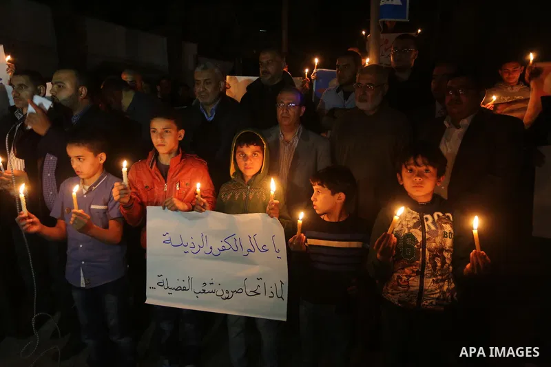 Supporters of the Palestinian Hamas movement hold placards and light candles during a protest against the Israeli blockade of the Gaza Strip, in Gaza city, on April 14, 2017. Photo by Mohammed Asad