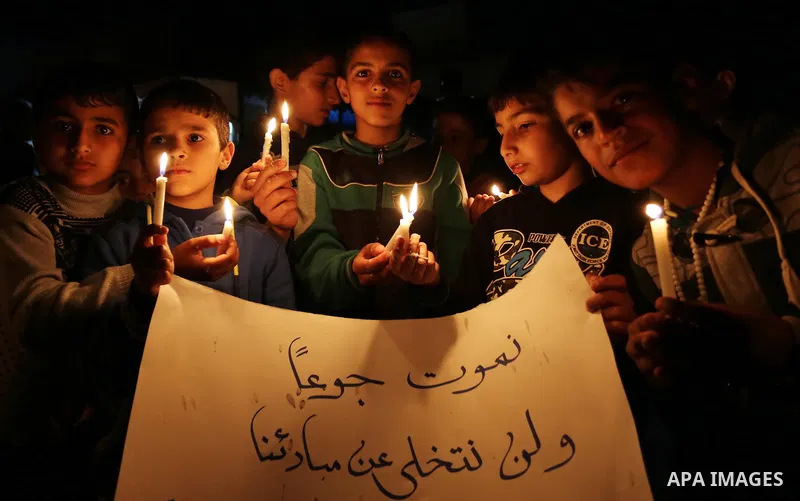 Supporters of the Palestinian Hamas movement hold placards and light candles during a protest against the Israeli blockade of the Gaza Strip, in Khan Younis in the southern Gaza Strip, on April 14, 2017. Photo by Ashraf...