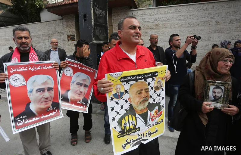 Palestinians hold placards during a protest to show solidarity with Palestinian prisoners held in Israeli Jails, in front of Red cross office in Gaza city, on April 17, 2017. Photo by Mohammed Asad