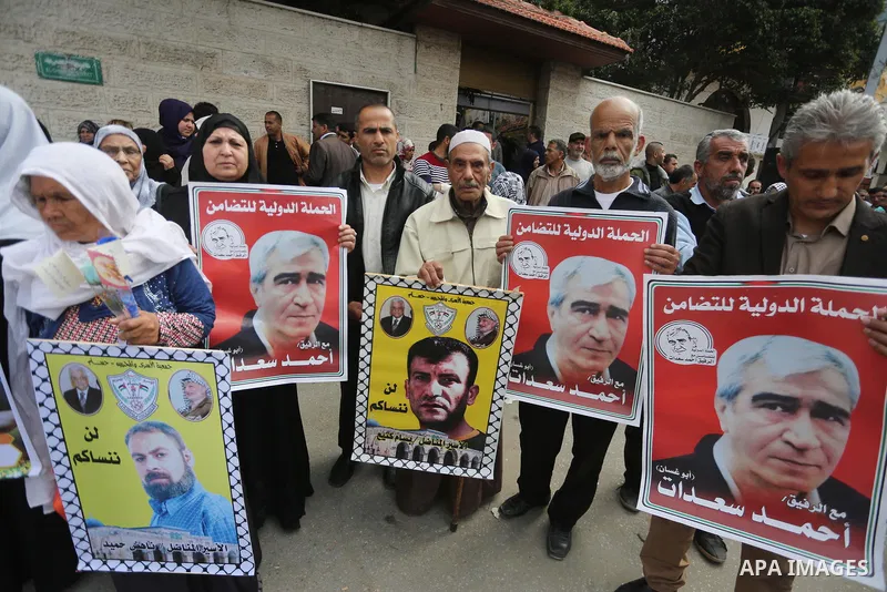 Palestinians hold placards during a protest to show solidarity with Palestinian prisoners held in Israeli Jails, in front of Red cross office in Gaza city, on April 17, 2017. Photo by Mohammed Asad