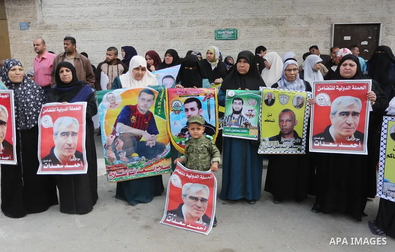 Palestinians hold placards during a protest to show solidarity with Palestinian prisoners held in Israeli Jails, in front of Red cross office in Gaza city, on April 17, 2017. Photo by Mohammed Asad