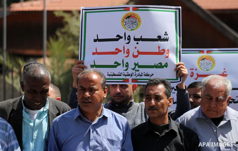 Palestinians hold placards during a demonstration against the decision to reduce their salaries in Gaza City on April 18, 2017. Photo by Mohammed Asad