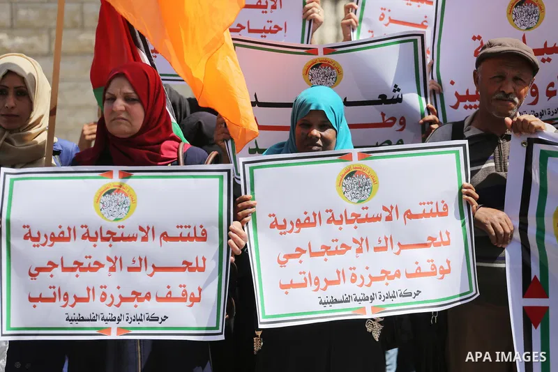 Palestinians hold placards during a demonstration against the decision to reduce their salaries in Gaza City on April 18, 2017. Photo by Mohammed Asad