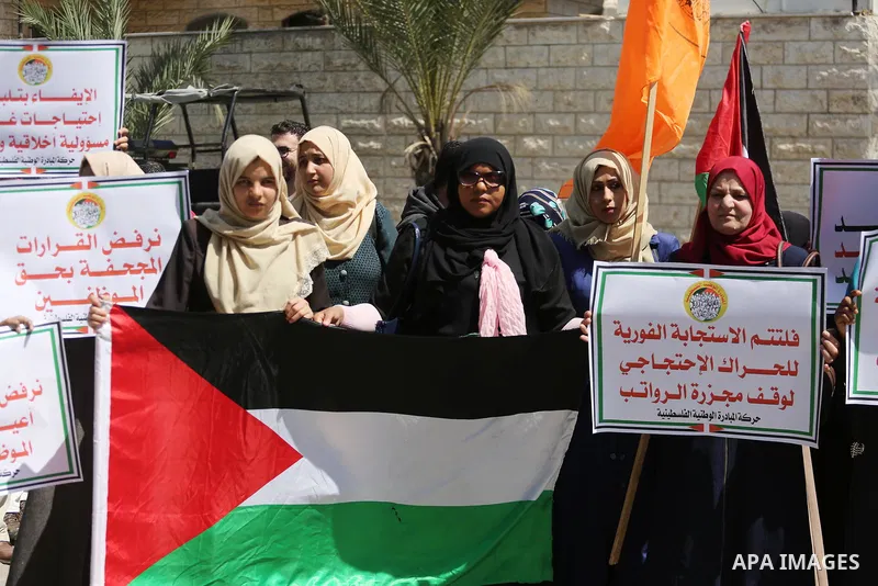 Palestinians hold placards during a demonstration against the decision to reduce their salaries in Gaza City on April 18, 2017. Photo by Mohammed Asad