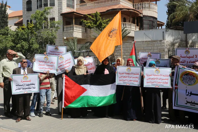 Palestinians hold placards during a demonstration against the decision to reduce their salaries in Gaza City on April 18, 2017. Photo by Mohammed Asad