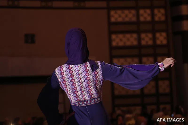 A picture taken on April 15, 2017 shows a Palestinian model displays a traditional Palestinian dress during a fashion show during the 2nd Nablus Festival for Culture and Arts, in the West Bank city of Nablus. The interna...