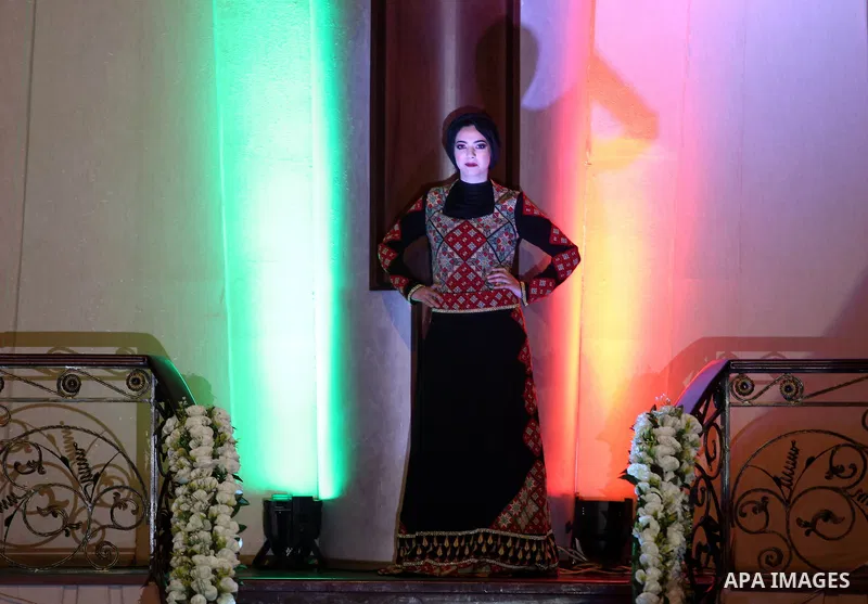 A picture taken on April 15, 2017 shows a Palestinian model displays a traditional Palestinian dress during a fashion show during the 2nd Nablus Festival for Culture and Arts, in the West Bank city of Nablus. The interna...