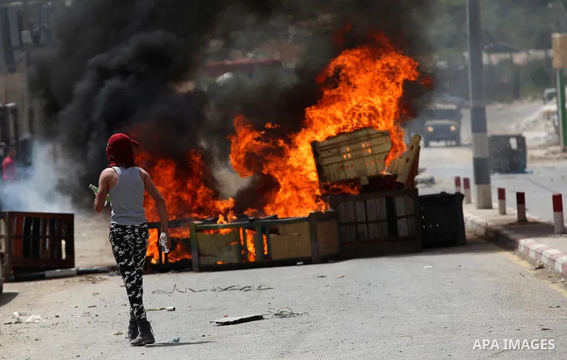 A Palestinian protester dodges teargas cannisters during clashes with Israeli forces in the West Bank village of Beita, southeast of Nablus city, after a protest took place following Friday prayers in solidarity with Pal...