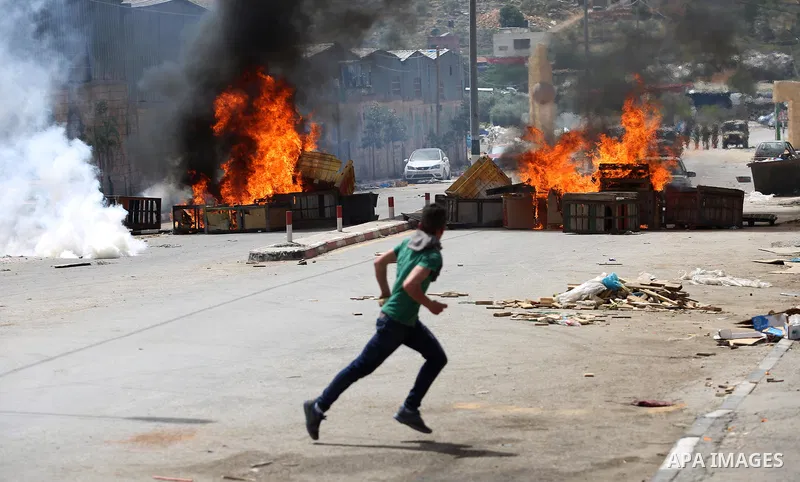 A Palestinian protester dodges teargas cannisters during clashes with Israeli forces in the West Bank village of Beita, southeast of Nablus city, after a protest took place following Friday prayers in solidarity with Pal...