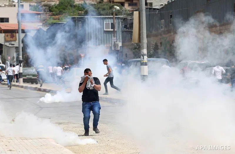 A Palestinian protester dodges teargas cannisters during clashes with Israeli forces in the West Bank village of Beita, southeast of Nablus city, after a protest took place following Friday prayers in solidarity with Pal...