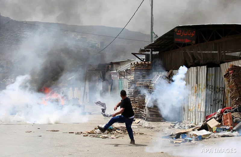 A Palestinian protester dodges teargas cannisters during clashes with Israeli forces in the West Bank village of Beita, southeast of Nablus city, after a protest took place following Friday prayers in solidarity with Pal...