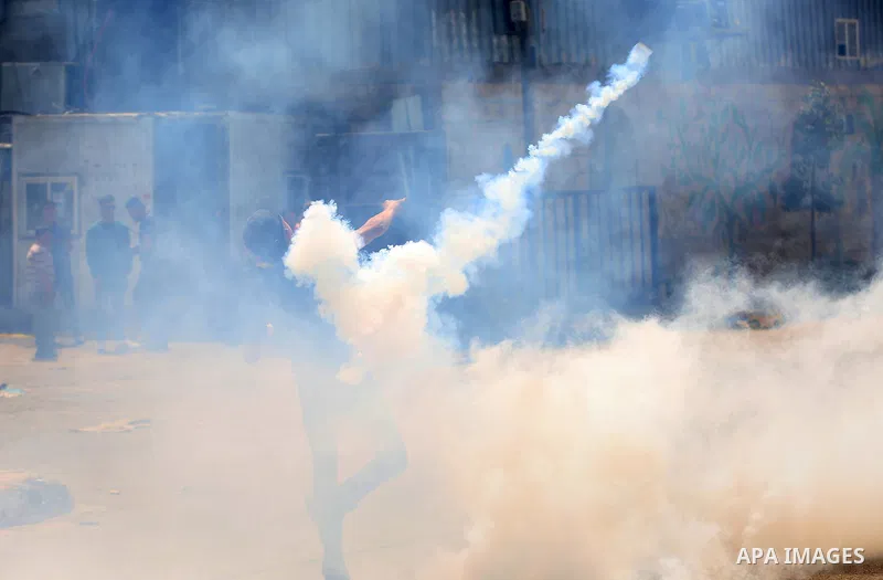 A Palestinian protester dodges teargas cannisters during clashes with Israeli forces in the West Bank village of Beita, southeast of Nablus city, after a protest took place following Friday prayers in solidarity with Pal...