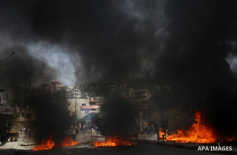 A Palestinian protester dodges teargas cannisters during clashes with Israeli forces in the West Bank village of Beita, southeast of Nablus city, after a protest took place following Friday prayers in solidarity with Pal...