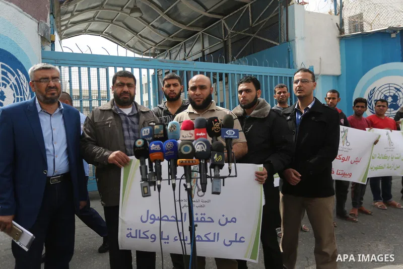 Palestinians hold banners during a protest to demand UNRWA provide electricity to refugee camps, in Gaza city, on April 23, 2017. Photo by Mohammed Asad