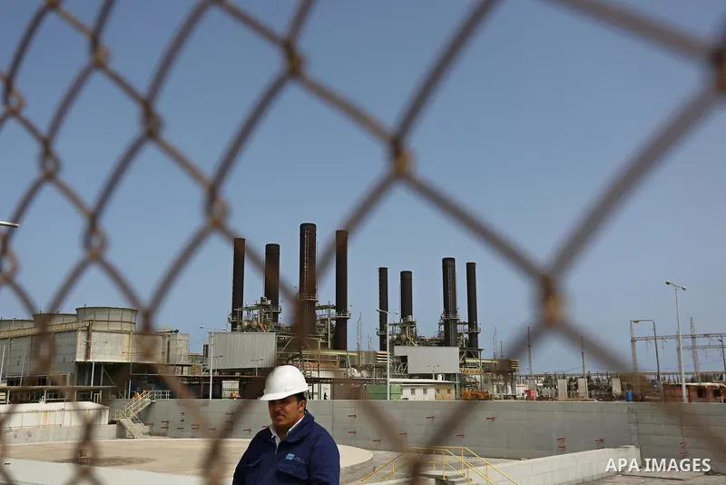 A Palestinian worker stands near the fence of the power plant during a protest calling for an end to the power crisis, in the central Gaza Strip April 23, 2017. Photo by Ashraf Amra