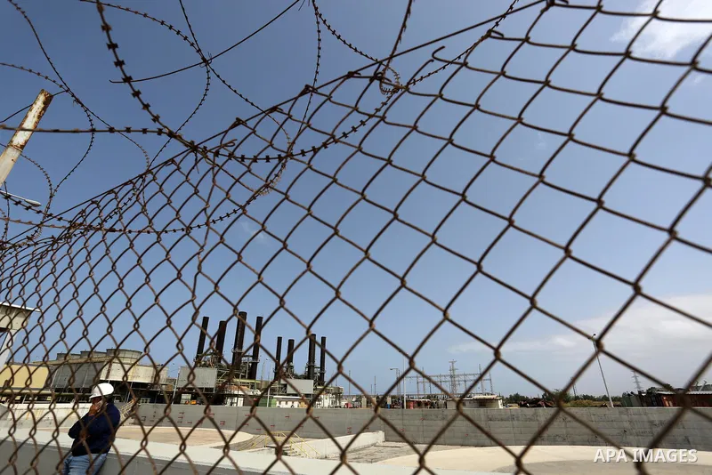 A Palestinian worker stands near the fence of the power plant during a protest calling for an end to the power crisis, in the central Gaza Strip April 23, 2017. Photo by Ashraf Amra