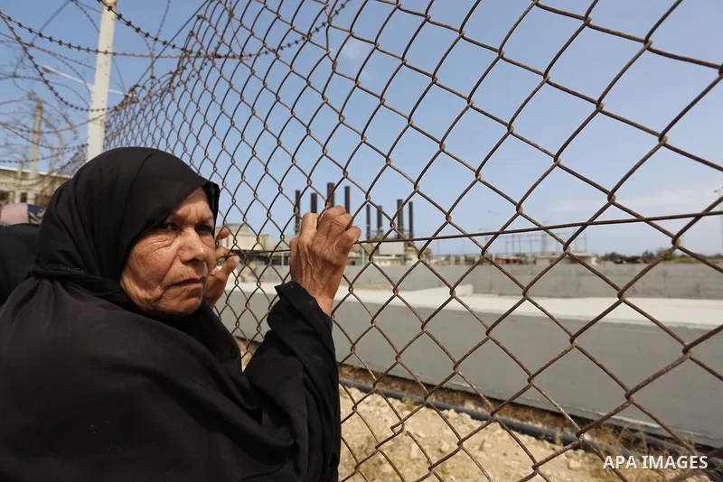 A Palestinian woman stands by a fence during a protest calling for an end to the power crisis, outside the power plant in the central Gaza Strip April 23, 2017. Photo by Ashraf Amra