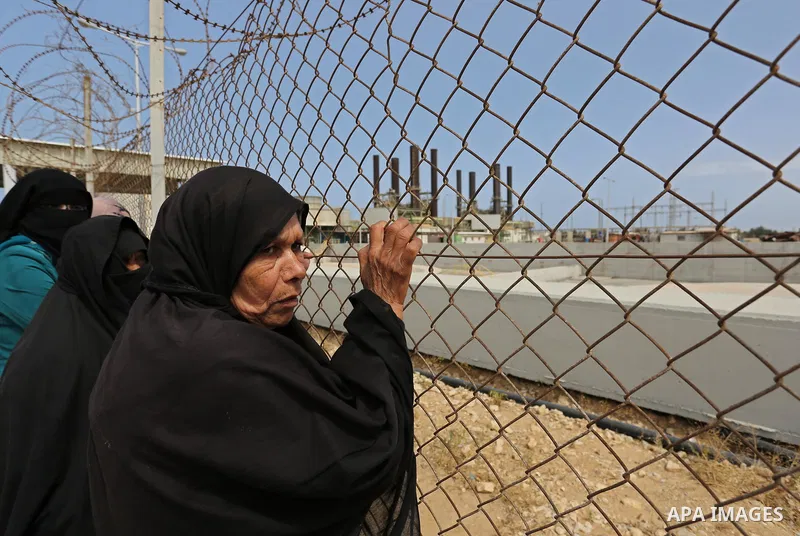 A Palestinian woman stands by a fence during a protest calling for an end to the power crisis, outside the power plant in the central Gaza Strip April 23, 2017. Photo by Ashraf Amra