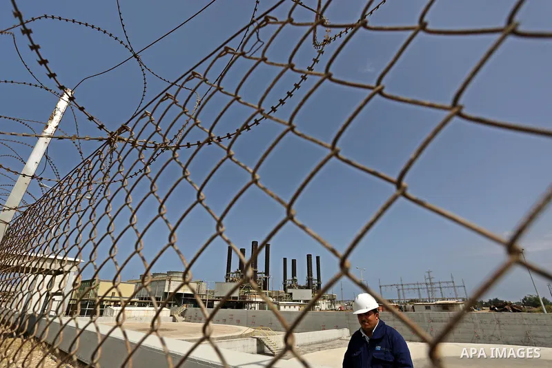 A Palestinian worker stands near the fence of the power plant during a protest calling for an end to the power crisis, in the central Gaza Strip April 23, 2017. Photo by Ashraf Amra