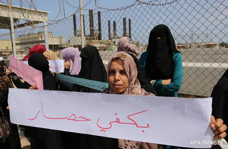Palestinian women hold banners during a protest calling for an end to the power crisis, outside the power plant in the central Gaza Strip April 23, 2017. Photo by Ashraf Amra
