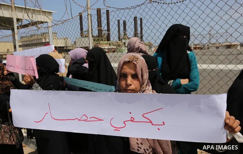 Palestinian women hold banners during a protest calling for an end to the power crisis, outside the power plant in the central Gaza Strip April 23, 2017. Photo by Ashraf Amra
