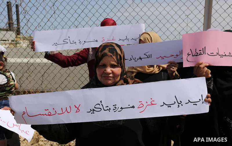 Palestinian women hold banners during a protest calling for an end to the power crisis, outside the power plant in the central Gaza Strip April 23, 2017. Photo by Ashraf Amra