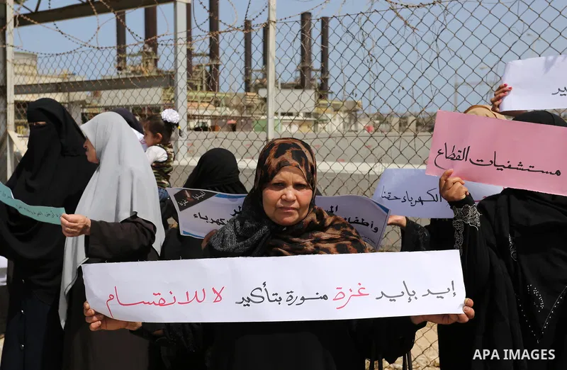 Palestinian women hold banners during a protest calling for an end to the power crisis, outside the power plant in the central Gaza Strip April 23, 2017. Photo by Ashraf Amra