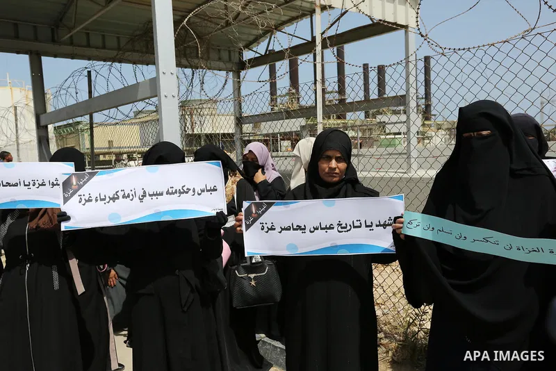 Palestinian women hold banners during a protest calling for an end to the power crisis, outside the power plant in the central Gaza Strip April 23, 2017. Photo by Ashraf Amra