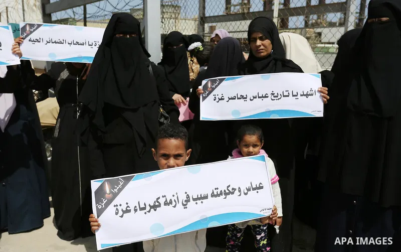Palestinian women hold banners during a protest calling for an end to the power crisis, outside the power plant in the central Gaza Strip April 23, 2017. Photo by Ashraf Amra