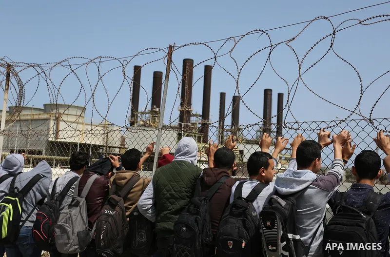 Palestinian school boys stand by a fence during a protest calling for an end to the power crisis, outside the power plant in the central Gaza Strip April 23, 2017. Photo by Ashraf Amra