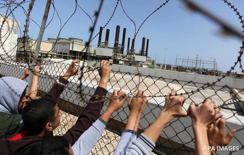 Palestinian school boys stand by a fence during a protest calling for an end to the power crisis, outside the power plant in the central Gaza Strip April 23, 2017. Photo by Ashraf Amra
