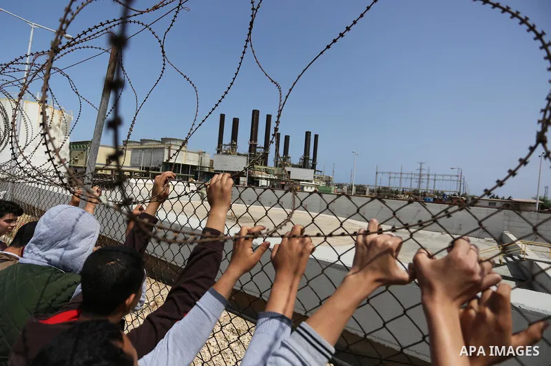 Palestinian school boys stand by a fence during a protest calling for an end to the power crisis, outside the power plant in the central Gaza Strip April 23, 2017. Photo by Ashraf Amra