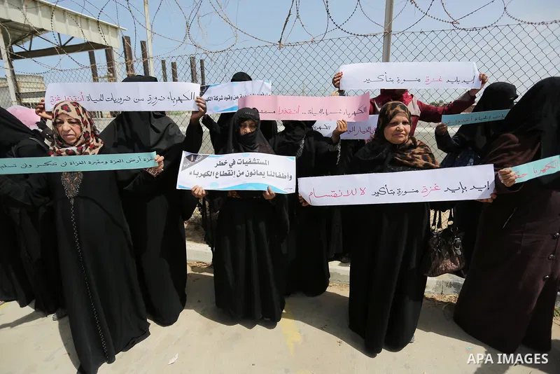 Palestinian women hold banners during a protest calling for an end to the power crisis, outside the power plant in the central Gaza Strip April 23, 2017. Photo by Ashraf Amra