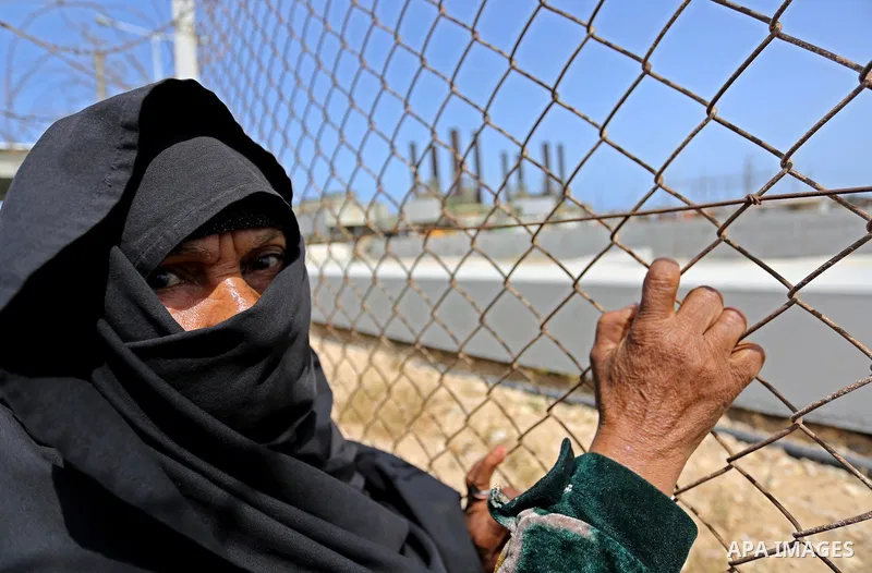 A Palestinian woman stands by a fence during a protest calling for an end to the power crisis, outside the power plant in the central Gaza Strip April 23, 2017. Photo by Ashraf Amra