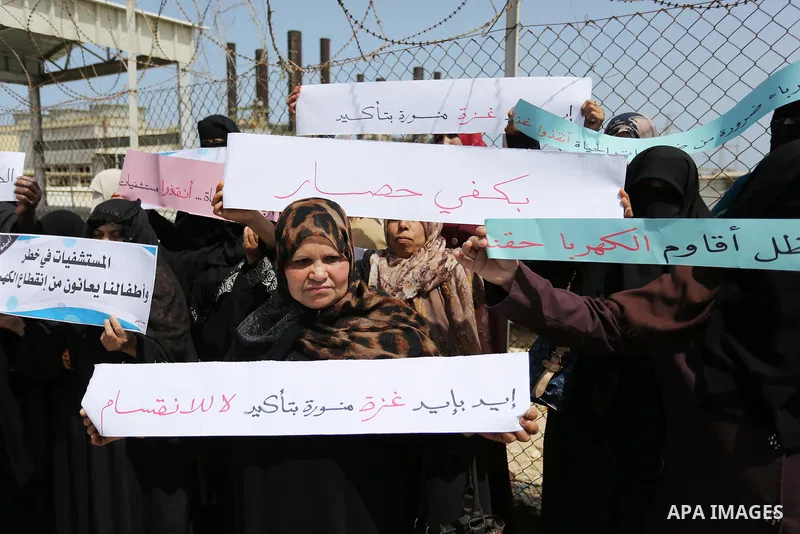 Palestinian women hold banners during a protest calling for an end to the power crisis, outside the power plant in the central Gaza Strip April 23, 2017. Photo by Ashraf Amra