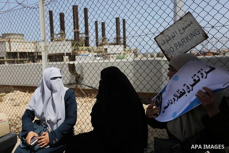 Palestinian women hold banners during a protest calling for an end to the power crisis, outside the power plant in the central Gaza Strip April 23, 2017. Photo by Ashraf Amra