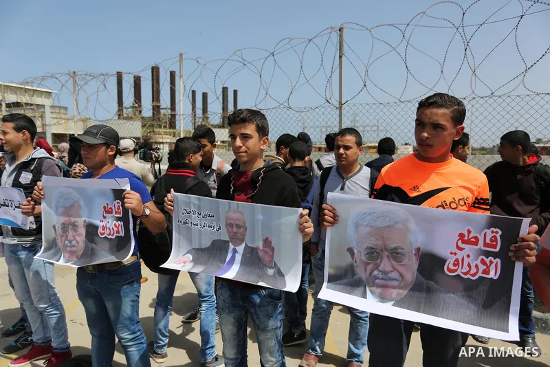 Palestinian women hold banners during a protest calling for an end to the power crisis, outside the power plant in the central Gaza Strip April 23, 2017. Photo by Ashraf Amra